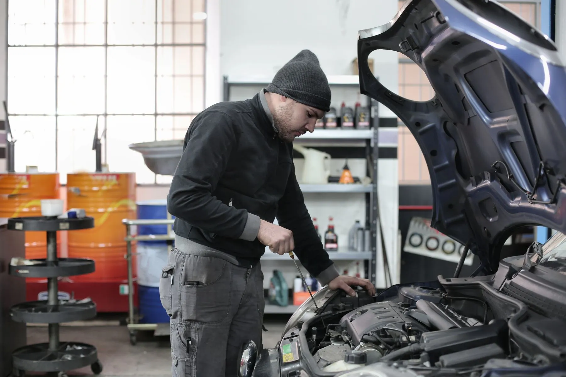 Szerelő egy személyautó motorterét ellenőrzi a műhelyben